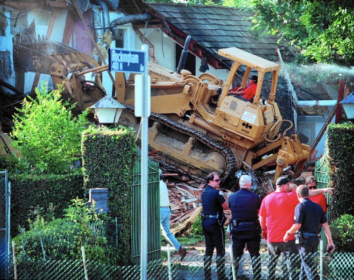 As police look on, a bulldozer knocks down the former home of O.J. Simpson in Brentwood on July 29, 1998.