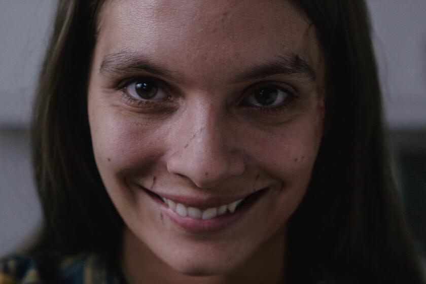 Close-up of a woman with an unnervingly broad grin and a scar