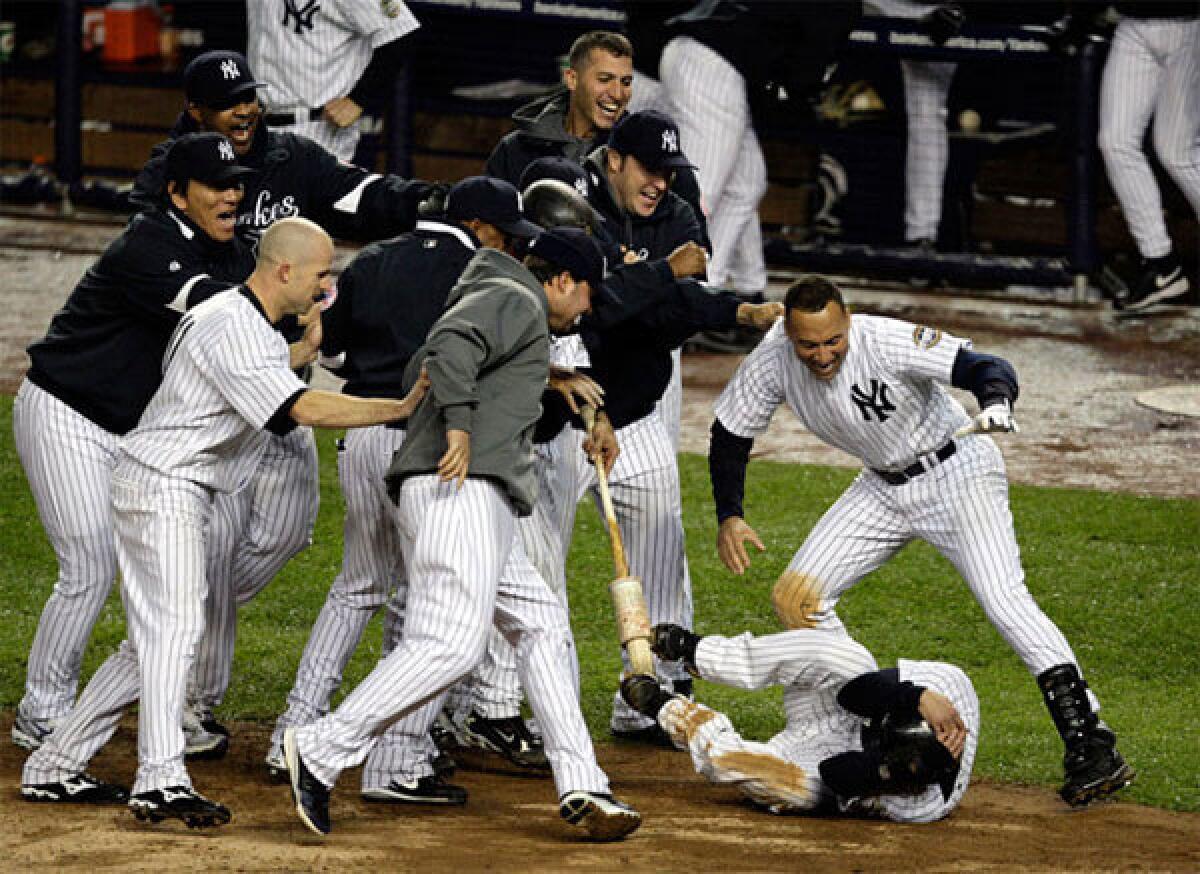 Yankees swarm Jerry Hairston Jr. after he scored the winning run beating the Angels, 4-3, in the 13th inning of Game 2 of the ALCS on Saturday night at Yankee Stadium.