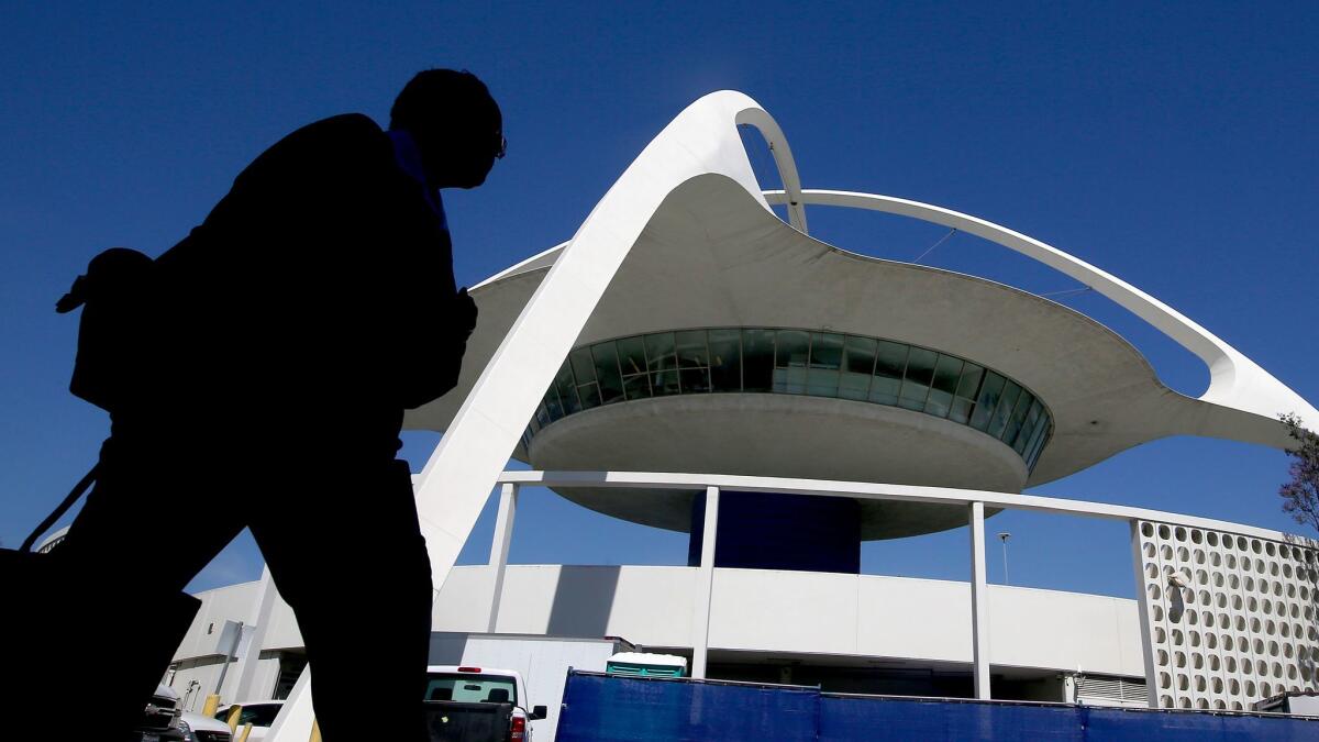 A pedestrian walks past the Theme Building between Terminals 2 and 6 at LAX.