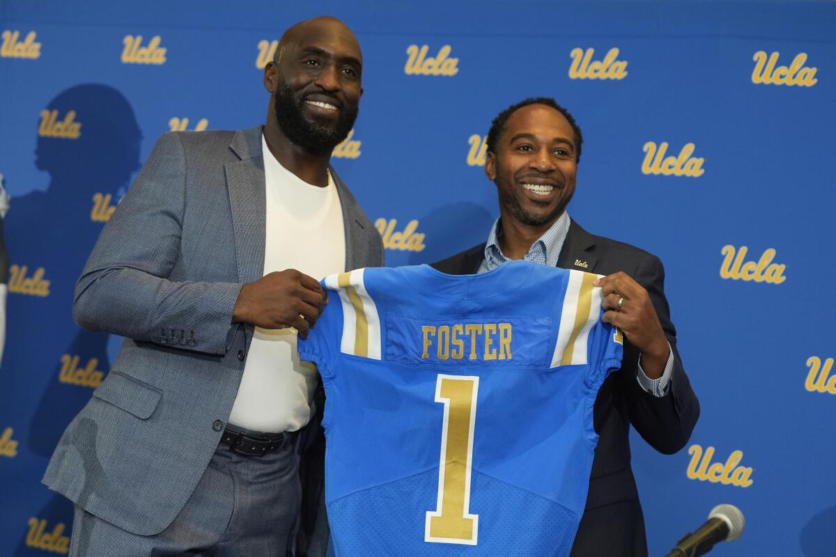 New UCLA football coach DeShaun Foster, left, poses with athletic director Martin Jarmond.