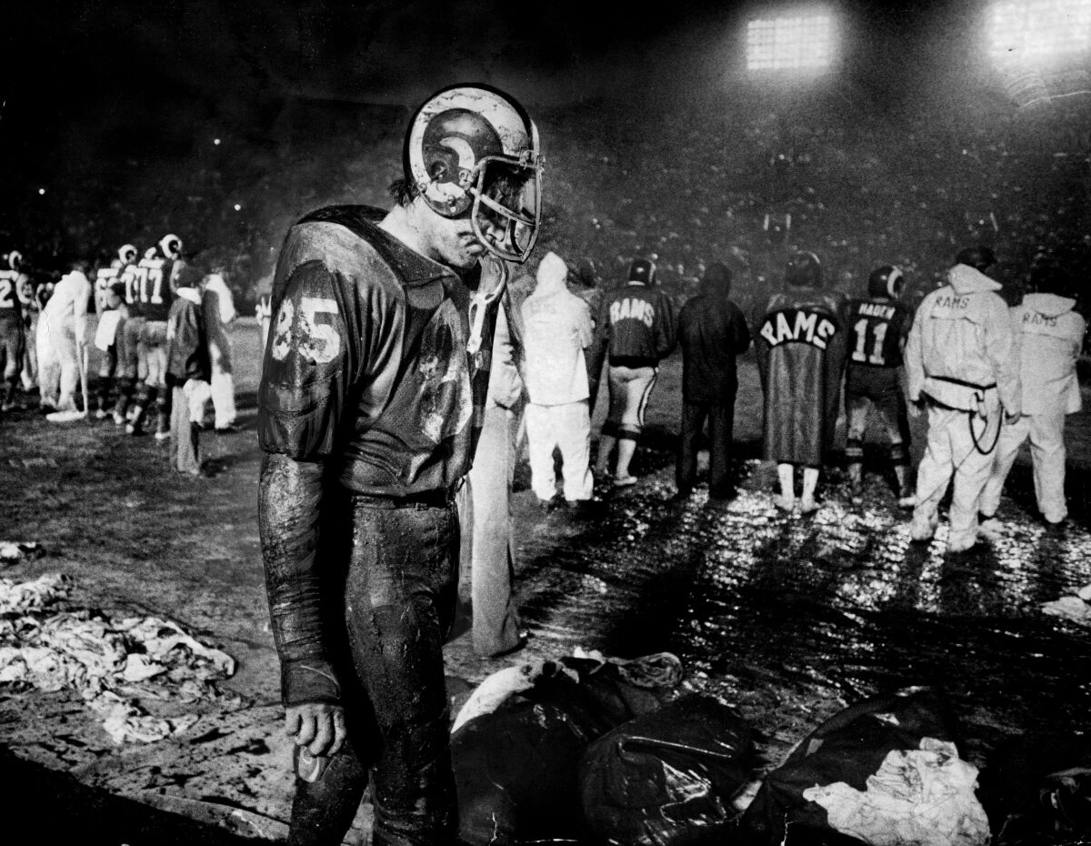 Muddied Rams defensive end Jack Youngblood walks on the sidelines as precipitation falls.