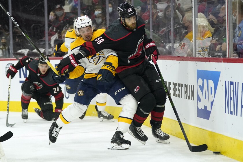 Nashville Predators left wing Erik Haula (56) and Carolina Hurricanes defenseman Jani Hakanpaa (58) skate for the puck during the first period in Game 1 of an NHL hockey Stanley Cup first-round playoff series in Raleigh, N.C., Monday, May 17, 2021. (AP Photo/Gerry Broome)
