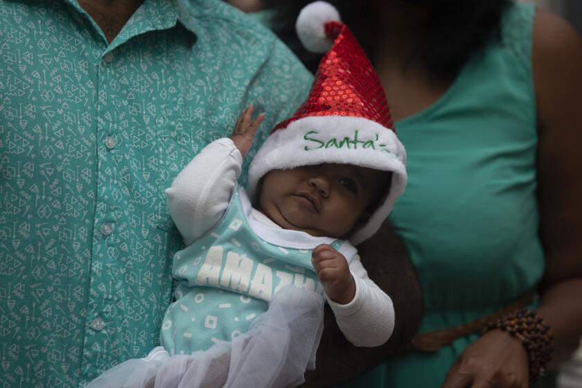 A baby is dressed in a Santa hat at a shopping mall in Johannesburg, South Africa, Tuesday, Dec. 22, 2020. (AP Photo/Denis Farrell)