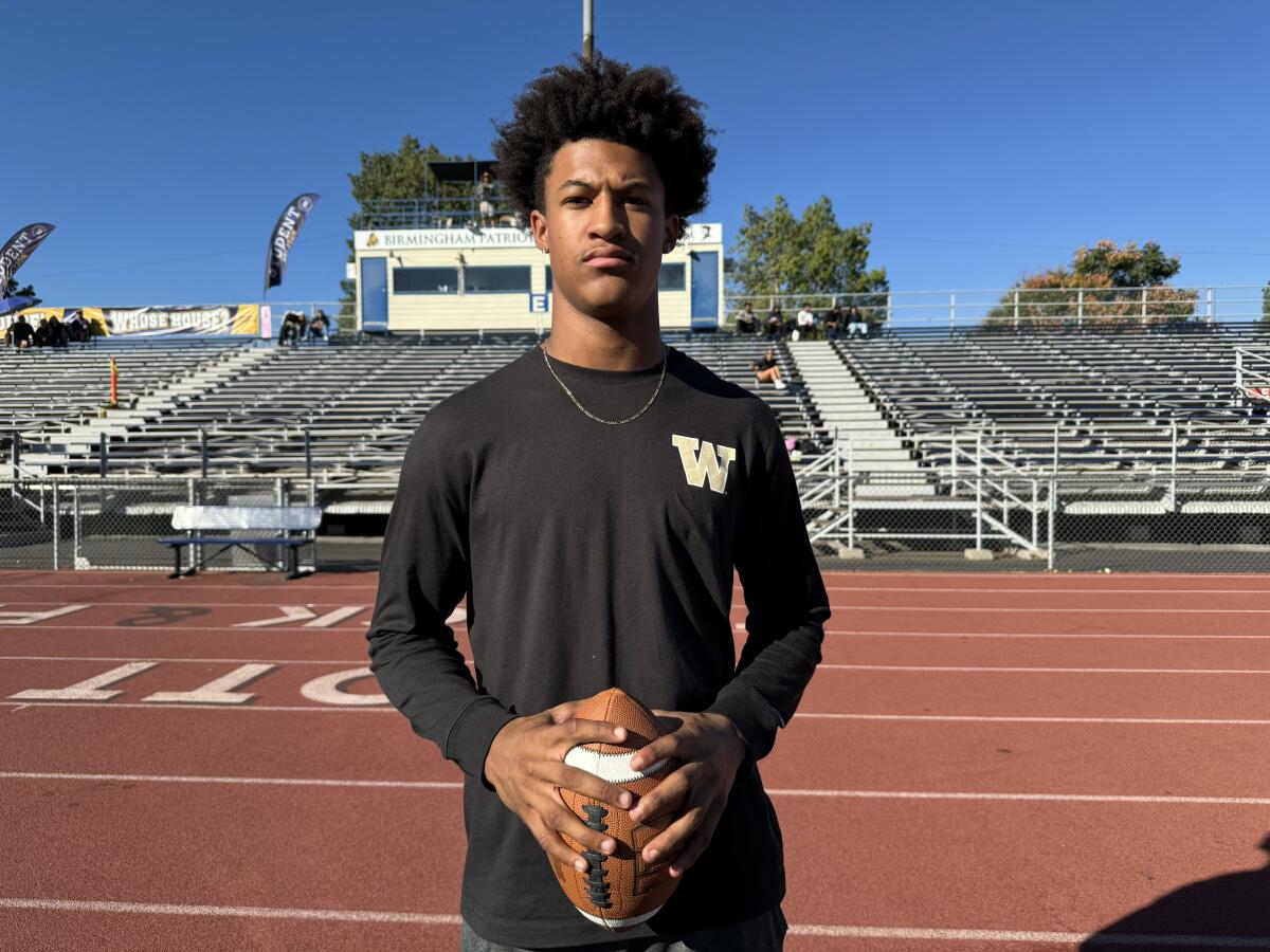 Peyton Waters holds a football in both hands as he poses for a photo at Birmingham High.