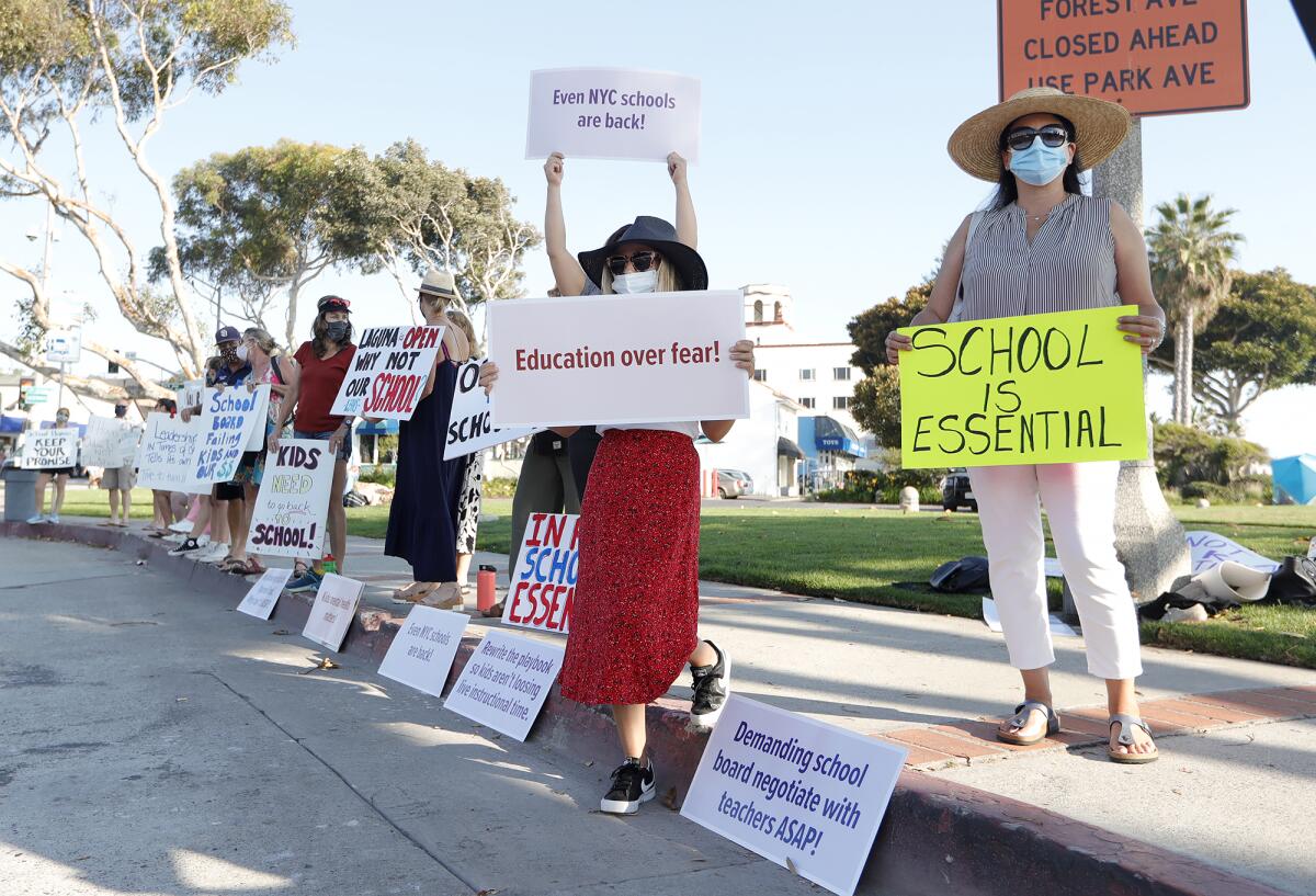 Laguna Beach parents demonstrate to open Thurston Middle School and Laguna Beach High School at Main Beach on Friday.