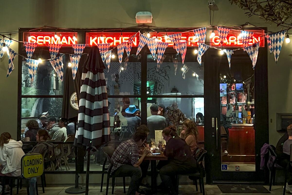 A well-lighted restaurant facade at night with people at tables.
