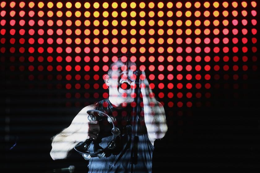 Trent Reznor leads his band Nine Inch Nails from behind a scrim of flashing lights at Staples Center on Friday.