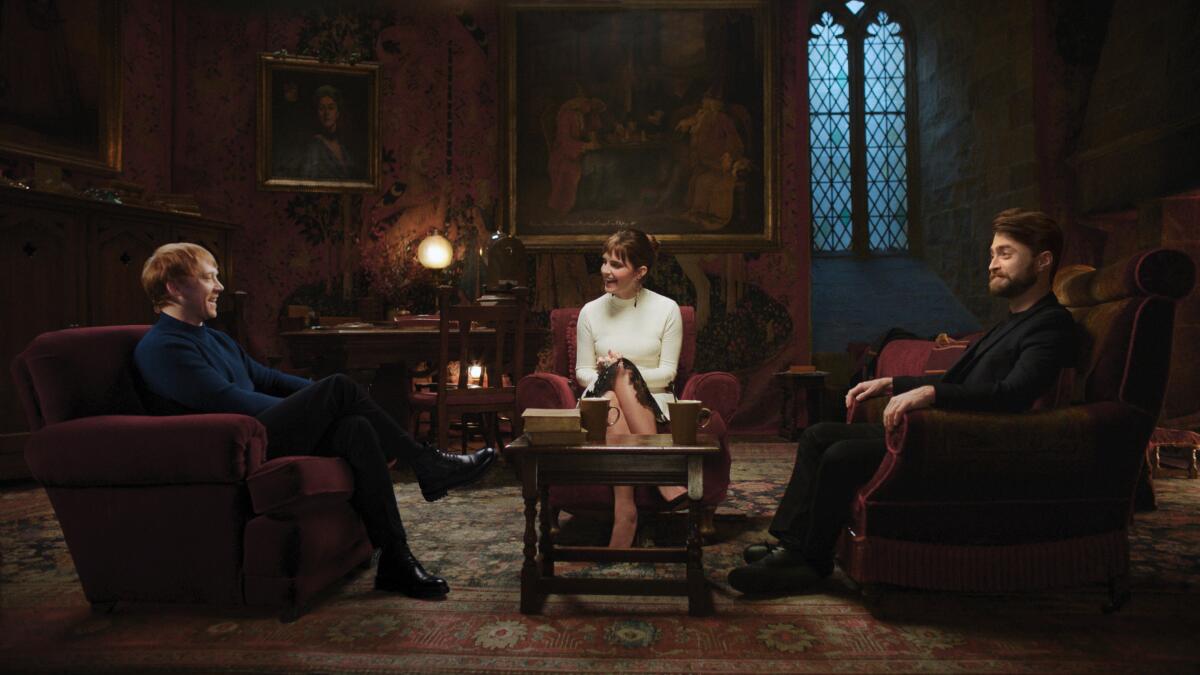Two men and a woman sitting in red armchairs