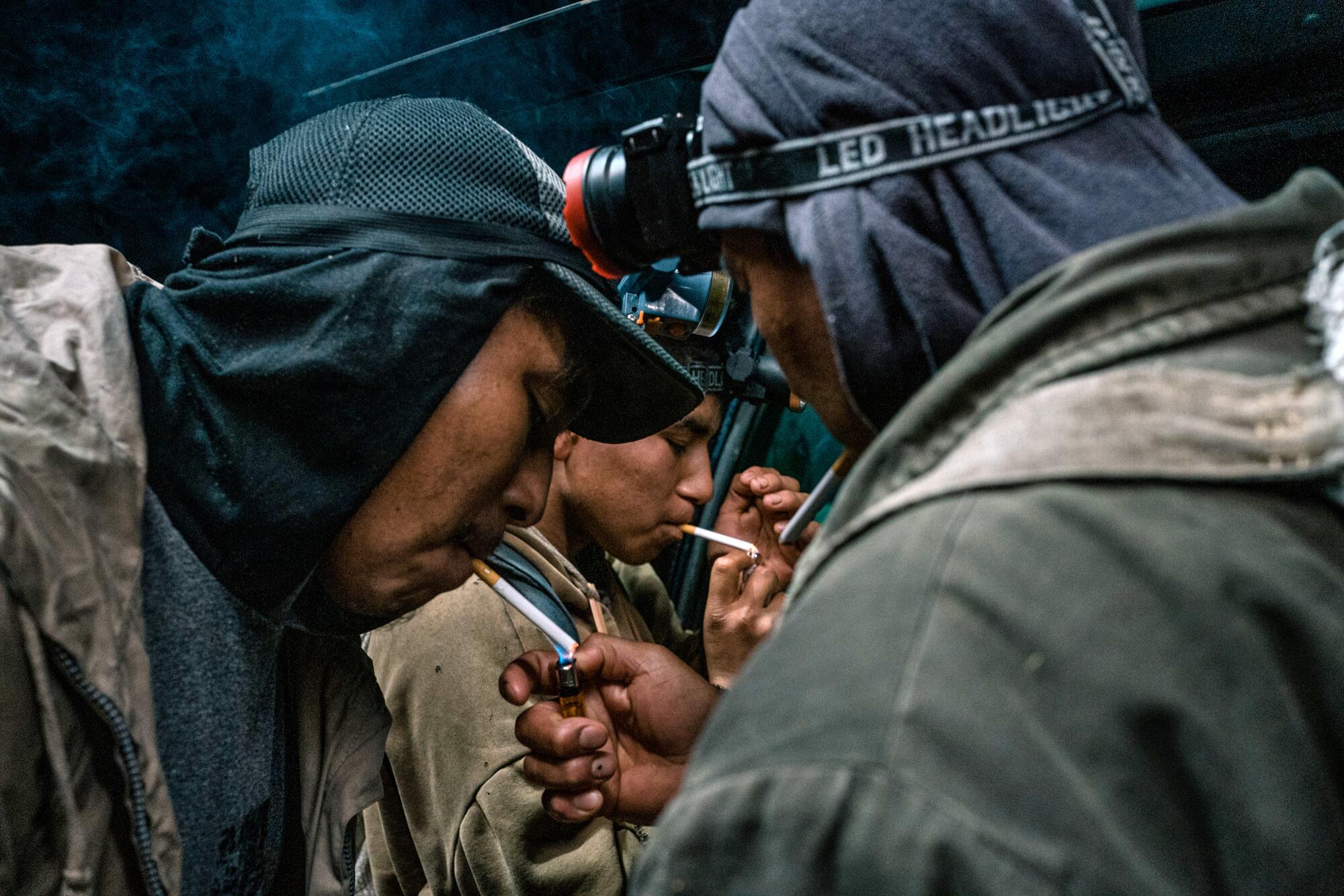 Men lean in to get a light for their cigarettes. 