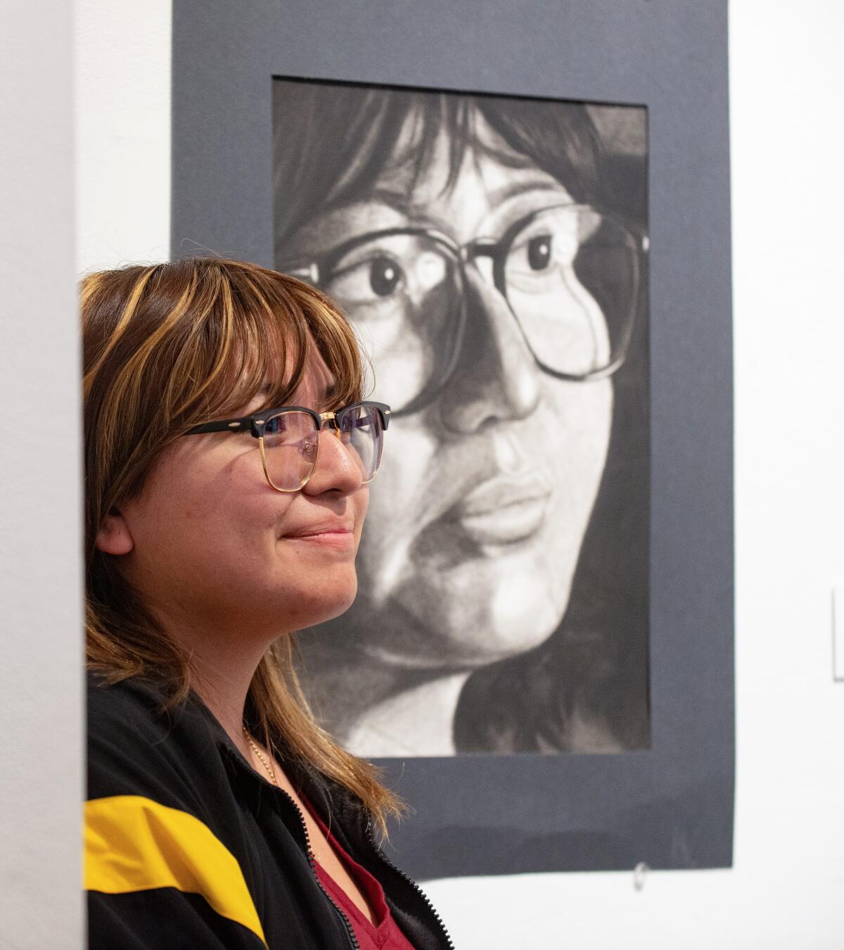 Santiago High junior Kenia Pais poses next to her drawing, "Resolute," at the LCAD Gallery through April 21.