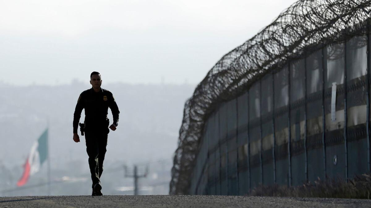 Border Patrol agent Eduardo Olmos walks near the secondary fence separating Tijuana, Mexico, and San Diego in 2016.