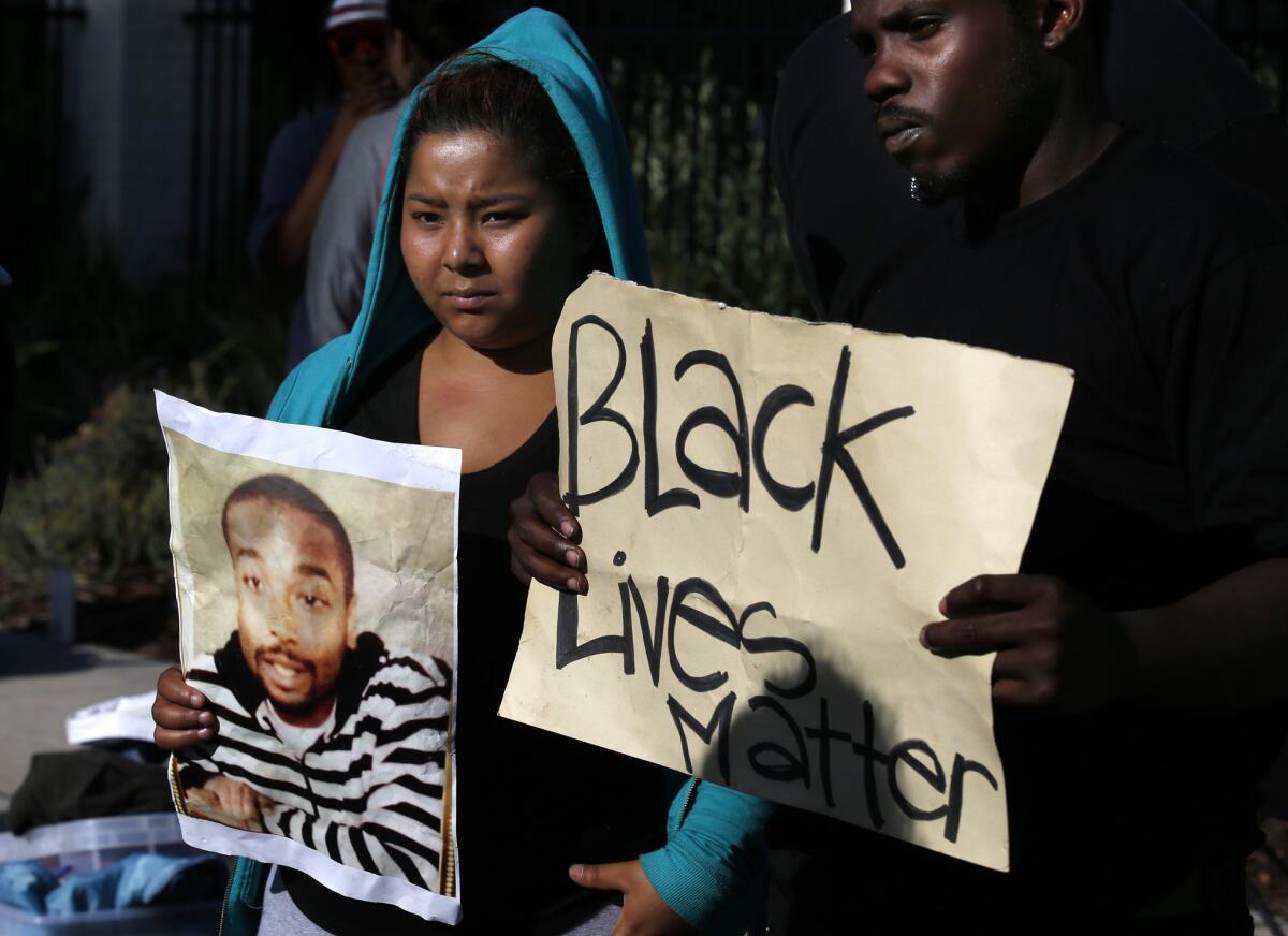 Activists with Black Lives Matter protest in Los Angeles in June. The person on the left is holding a photograph of Ezell Ford, who was killed by L.A. police officers on Aug. 11, 2014.