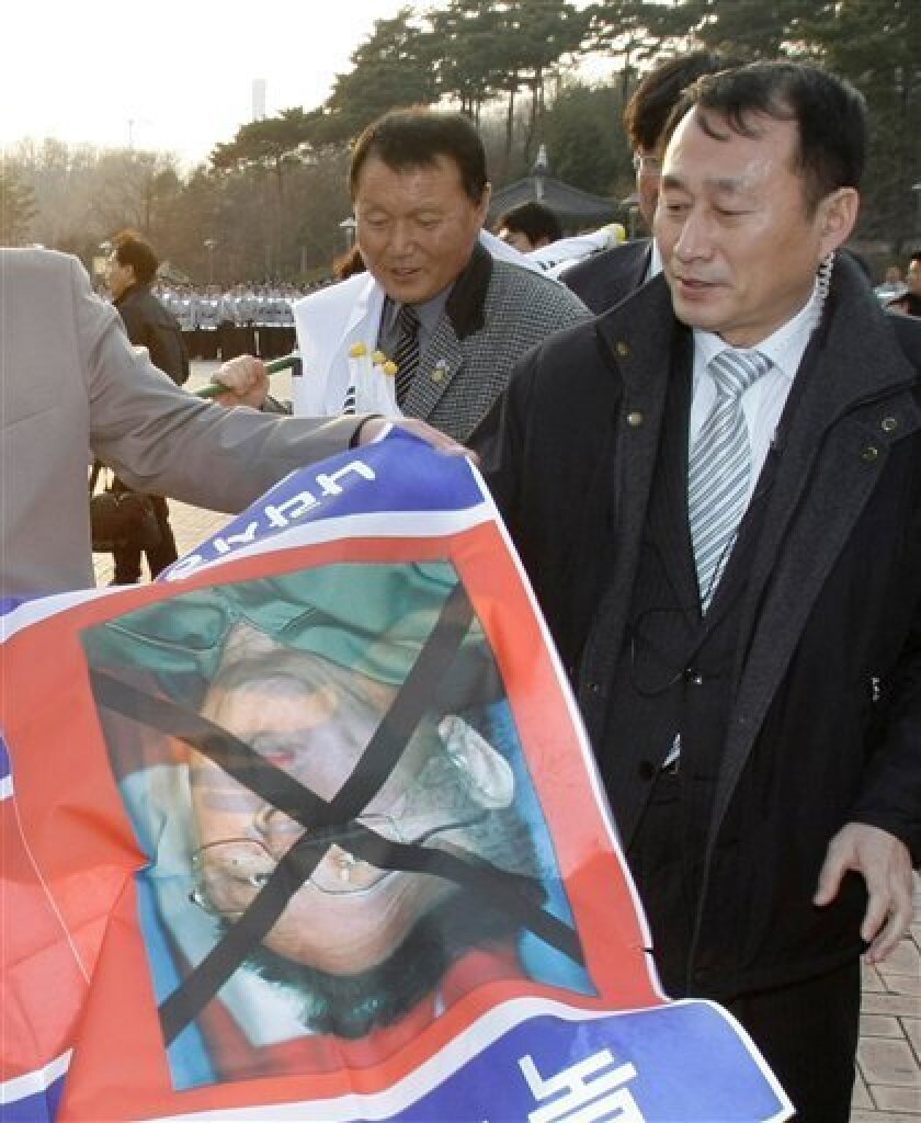 South Korean police officer, right, tries to take away a banner carrying North Korean flag and a picture of North Korean leader Kim Jong Il from protesters during a rally in front of Seoul World Cup stadium before the soccer match between two Koreas in Seoul, South Korea, Wednesday, April 1, 2009. North Korea accused the United States of spying on the site of an impending rocket launch and threatened Wednesday to shoot down any U.S. planes that intrude into its airspace. (AP Photo/Lee Jin-man)