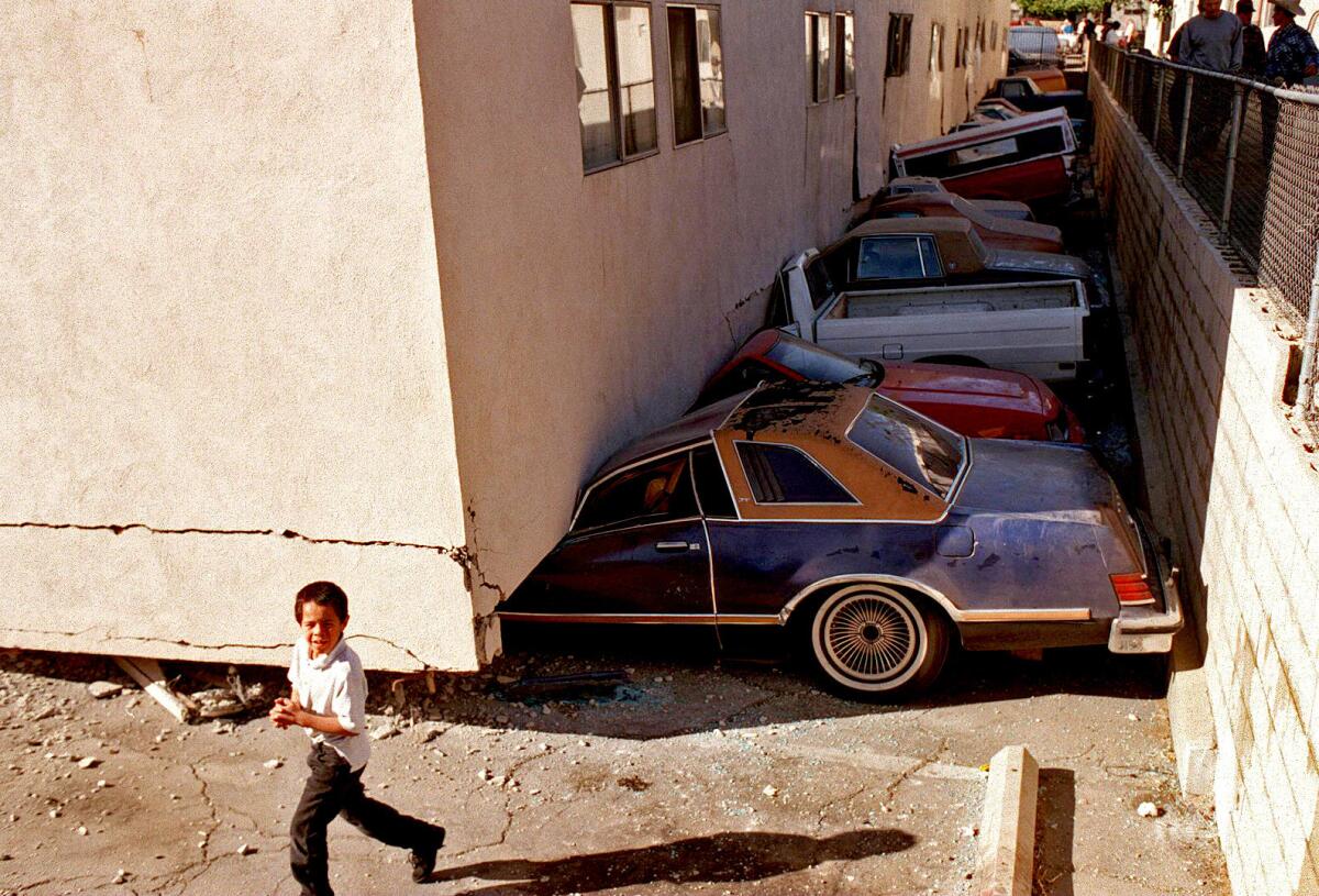 A row of cars is crushed beneath a collapsed apartment building in Canoga Park.