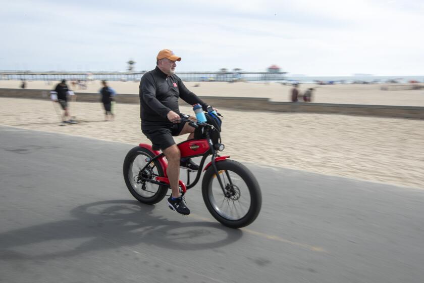 A man rides an e-bike on the bike path in Huntington Beach on Wednesday, April 7.