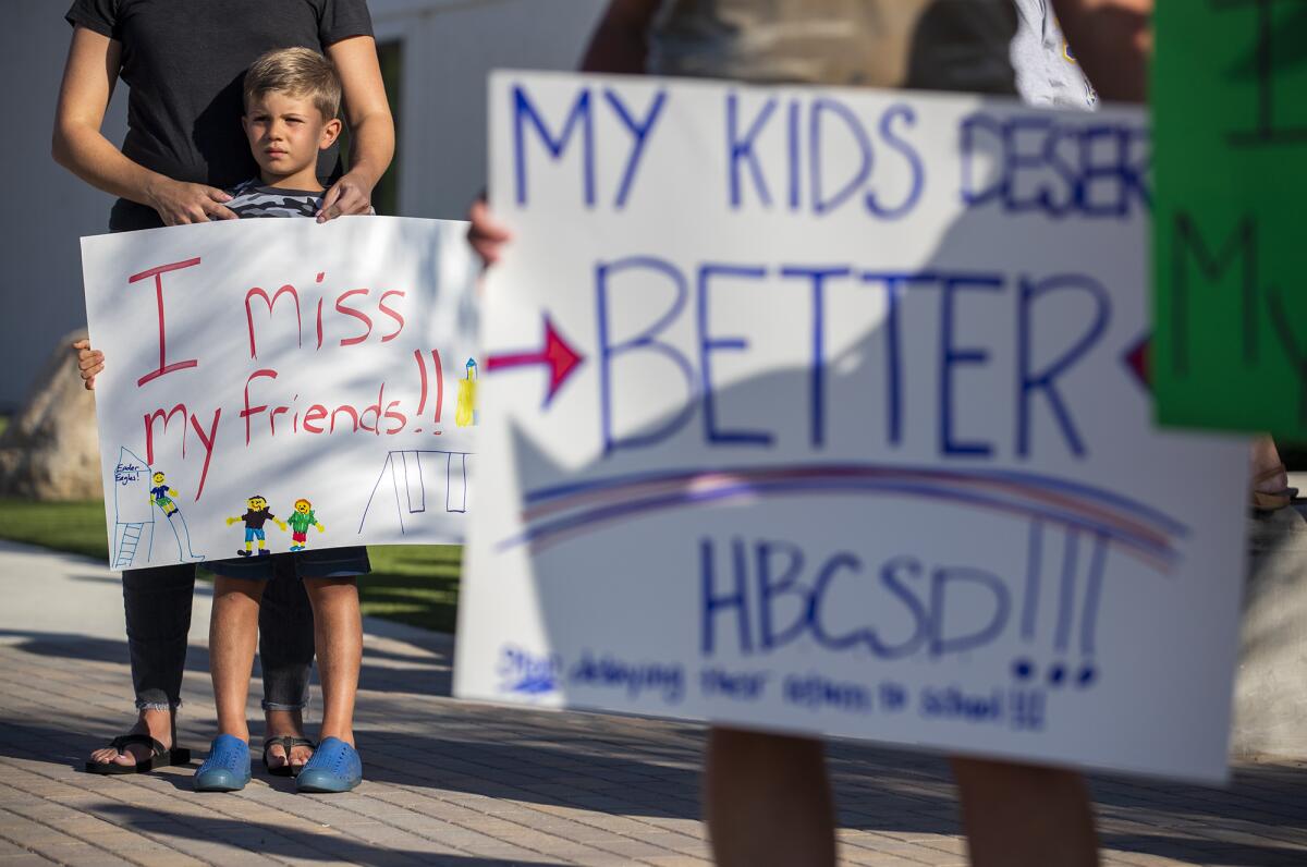 Julie Zarvos and her son, Ace Zarvos, 6, attend a rally at the Huntington Beach City School District.