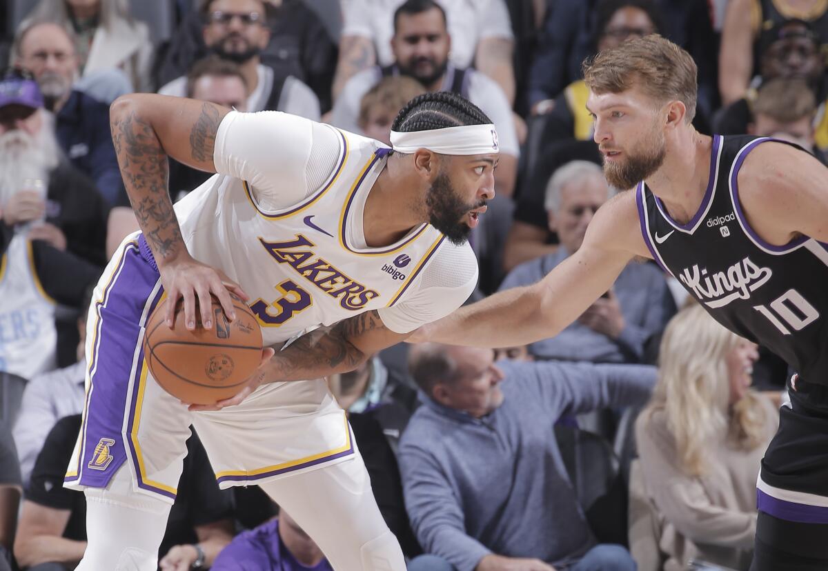 Lakers forward Anthony Davis, left, controls the ball in front of Kings forward Domantas Sabonis.