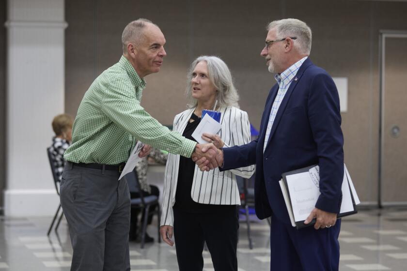 FILE - Paddy McGuire, Democrat incumbent Mason County auditor, left, shakes hands with his election opponent Republican Steve Duenkel, right, before a candidate forum, Oct. 13, 2022, in Shelton, Wash. Between is Mason County Commissioner Sharon Trask. (AP Photo/John Froschauer, File)