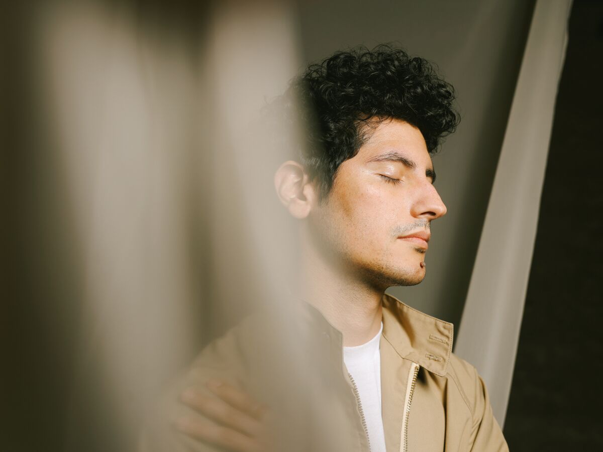 A man wearing a khaki jacket is seen in profile with his eyes closed.