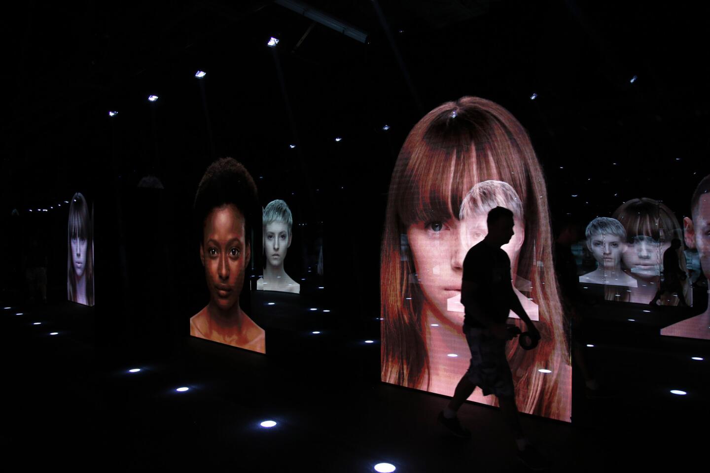 Images are projected onto mirrors lining a hallway at the exhibition. The interactive, multimedia experience lets visitors go behind the scenes of creating a runway collection and staging a fashion show. Admission is free.