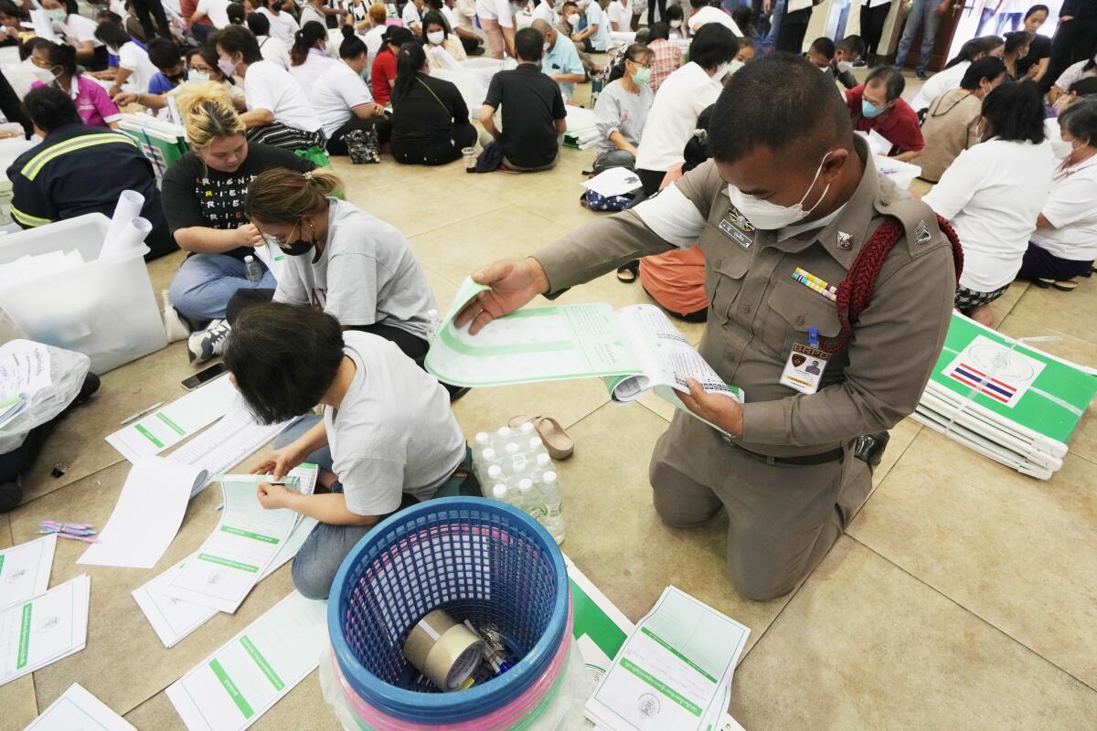 Volunteers and a police officer check ballots for Sunday's general election in Bangkok.