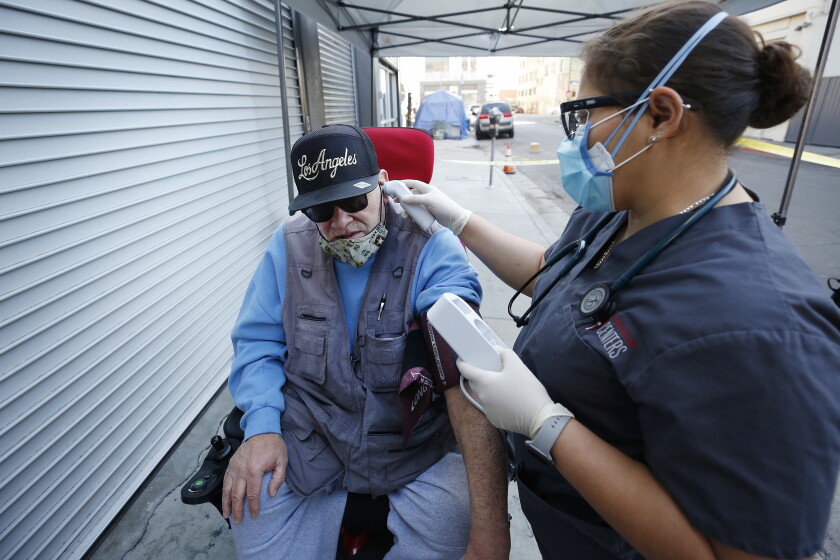 LOS ANGELES, CA - FEBRUARY 05: Medical Assistant Rosibel Giron checks temperature of Stanley Martin, 64, before he receives a COVID-19 vaccination shot as healthcare staff at Los Angeles Christian Health Centers, Joshua House Clinic on Winston Street in the Skid Row area of downtown Los Angeles are administering COVID-19 vaccinations to their community member/patient's this Friday morning. Skid Row on in Los Angeles, CA. (Al Seib / Los Angeles Times).