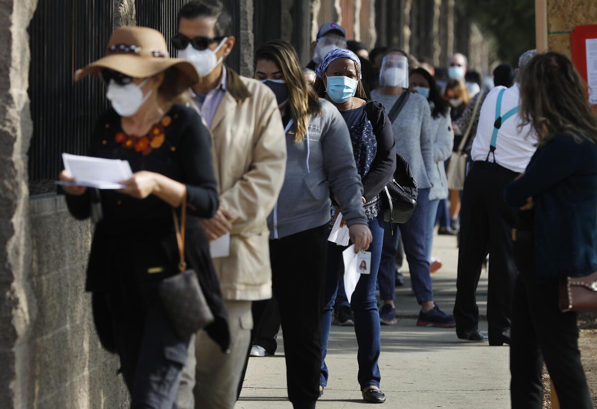 A line of people waiting to get vaccinated against COVID-19 stretches down the block