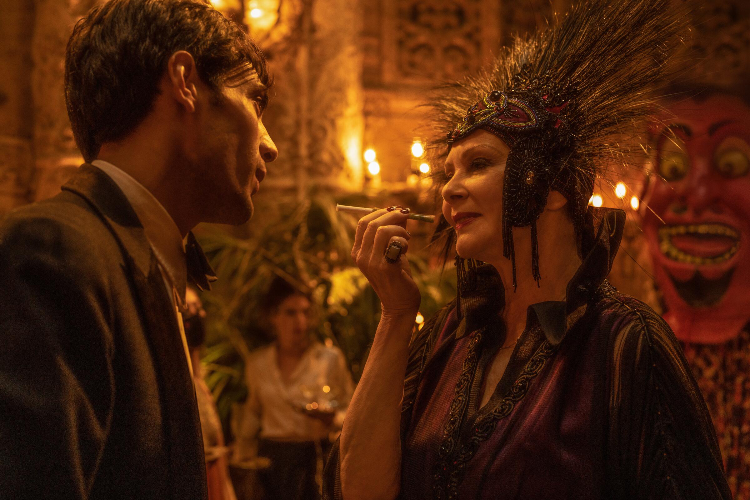 A man in a suit talks with a woman in a spiky headdress in a scene from "Babylon."