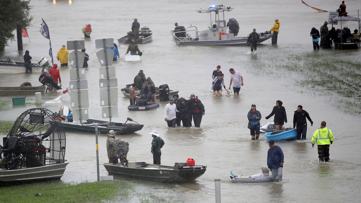 People walk down a flooded Houston street after evacuating homes and neighborhoods flooded by the rains from Tropical Storm Harvey.