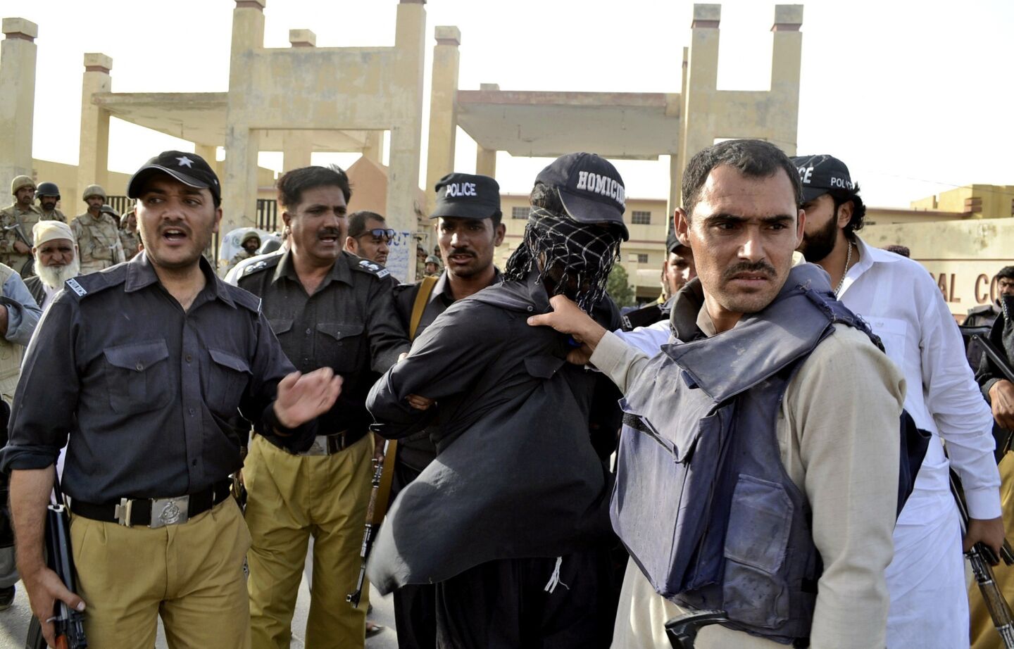 Pakistani police detain a suspected militant taken from the site of a gun battle at the Bolan Medical Complex in Quetta.