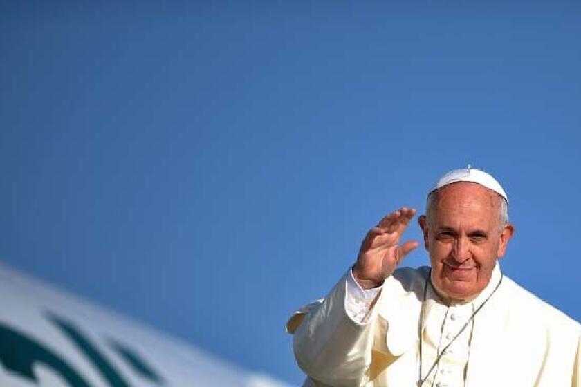 Pope Francis waves before entering his plane as he leaves Rome for Jordan.