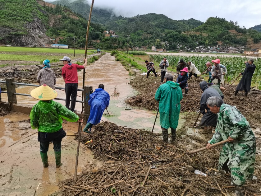 En esta imagen distribuida por la agencia noticiosa oficial Xinhua, varias personas trabajan en una zona anegada en el condado de Qiubei, en la provincia china de Yunnan, el 27 de mayo de 2022. (Xinhua vía AP)