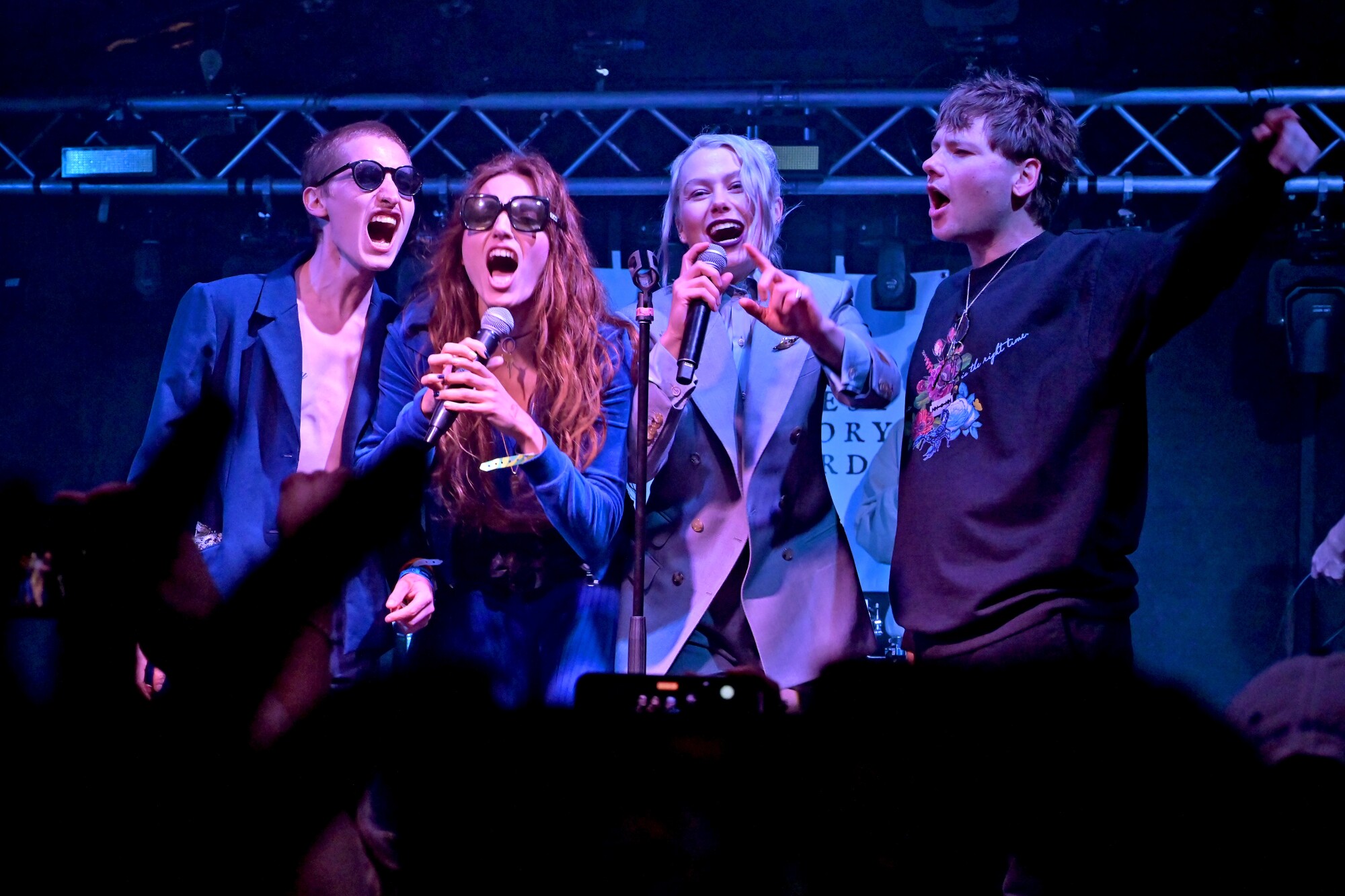 Four people singing together onstage.