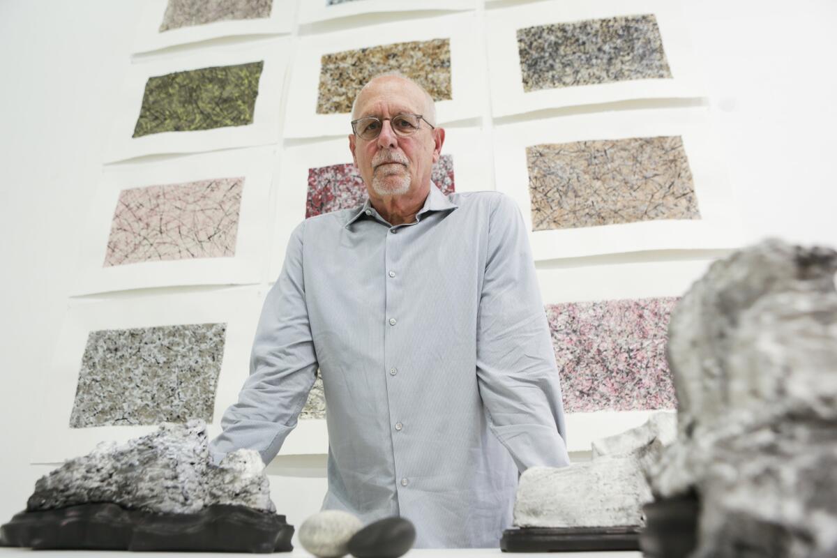 Artist and curator Richard Turner stands in front of his drawings of "Viewing Stones" at Chapman University's Guggenheim Gallery. The show features large stones shaped by erosion, as well as many artworks that were inspired by the various rocks and objects on display.