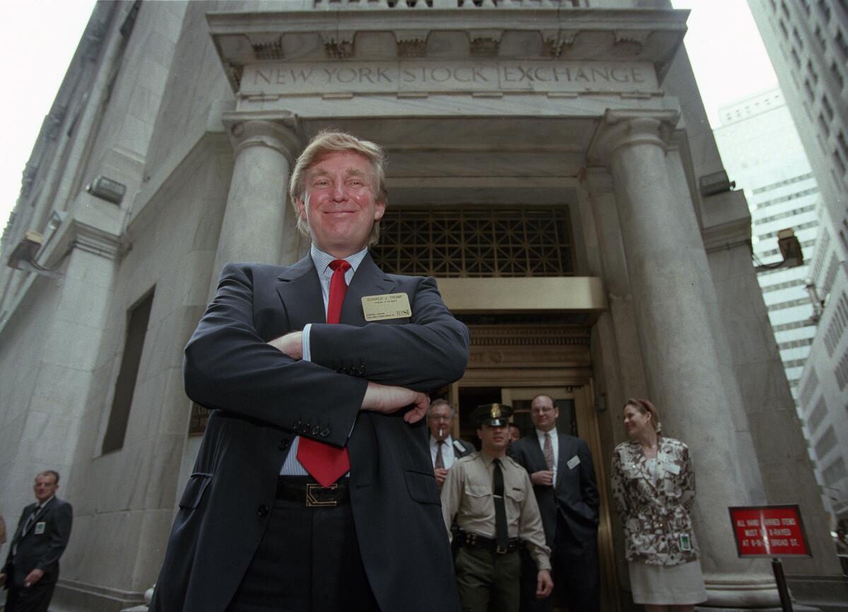 A younger Donald Trump smiles with folded arms outside the New York Stock Exchange.
