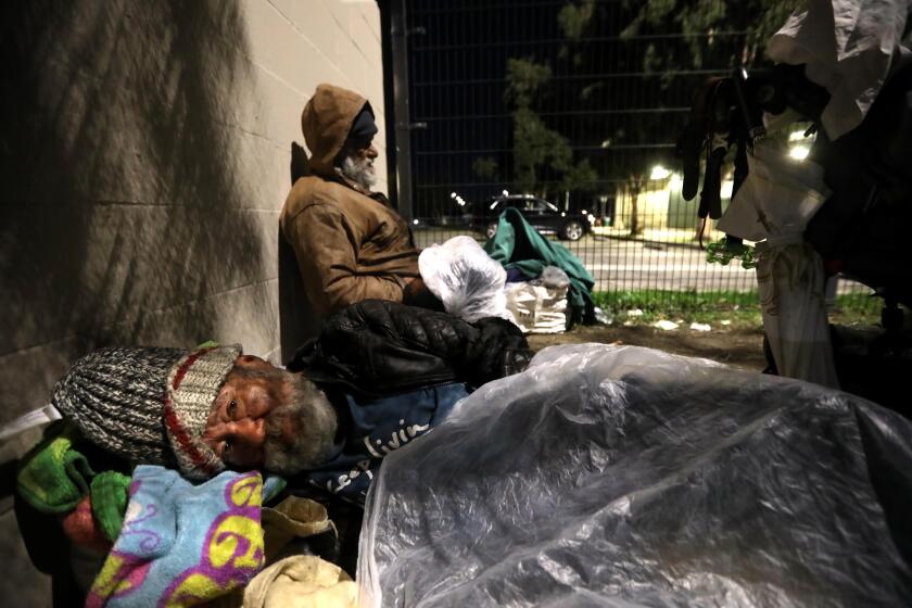 NORTH HOLLYWOOD, CA - JANUARY 23, 2024 - - Raul Moreda, 61, sleeps under a blanket of plastic while sharing an encampment with another homeless man at Tiara Street Park in North Hollywood on January 23, 2024. Moreda was counted as part of the first night of the Los Angeles Homeless Services Authority's 2024 homeless count in an effort to capture a point-in-time snapshot of the homelessness crisis impacting the region in North Hollywood. Moreda's friend, background, left before he could he counted. Los Angeles Mayor Karen Bass attended the presser, along with Supervisor Kathryn Barger, City Council member Nithya Raman, City Council President Paul Krekorian and LAHSA CEO Dr. Lecia Adams Kellum prior to the teams deploying. (Genaro Molina/Los Angeles Times)