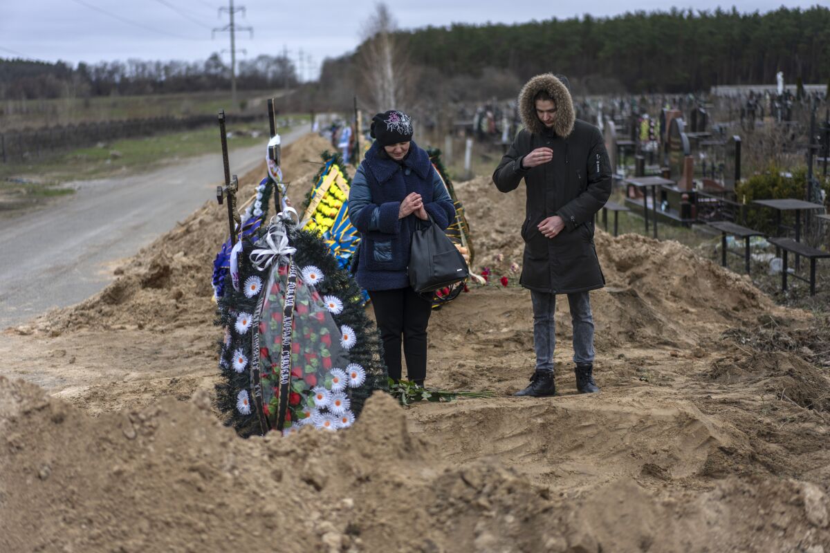 Natalya Verbova, 49, and her son Roman Verbovyi, 23, attend the funeral of her husband Andriy Verbovyi, 55, who was killed by Russian soldiers while serving in Bucha territorial defense, in the outskirts of Kyiv, Ukraine, Wednesday , April 13, 2022. (AP Photo/Rodrigo Abd)