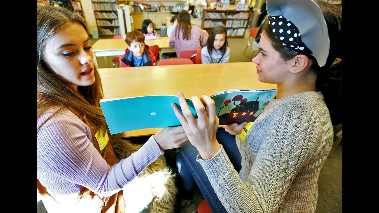 La Canada High School junior and French student Paris Papac, left, reads a book in French to La Canada Elementary School students as classmate Gwendalyn Stilson translates into English, at the school’s library in La Canada Flintridge on Thursday, Feb. 22, 2018. The two students wrote the book titled L’elephant pedait.