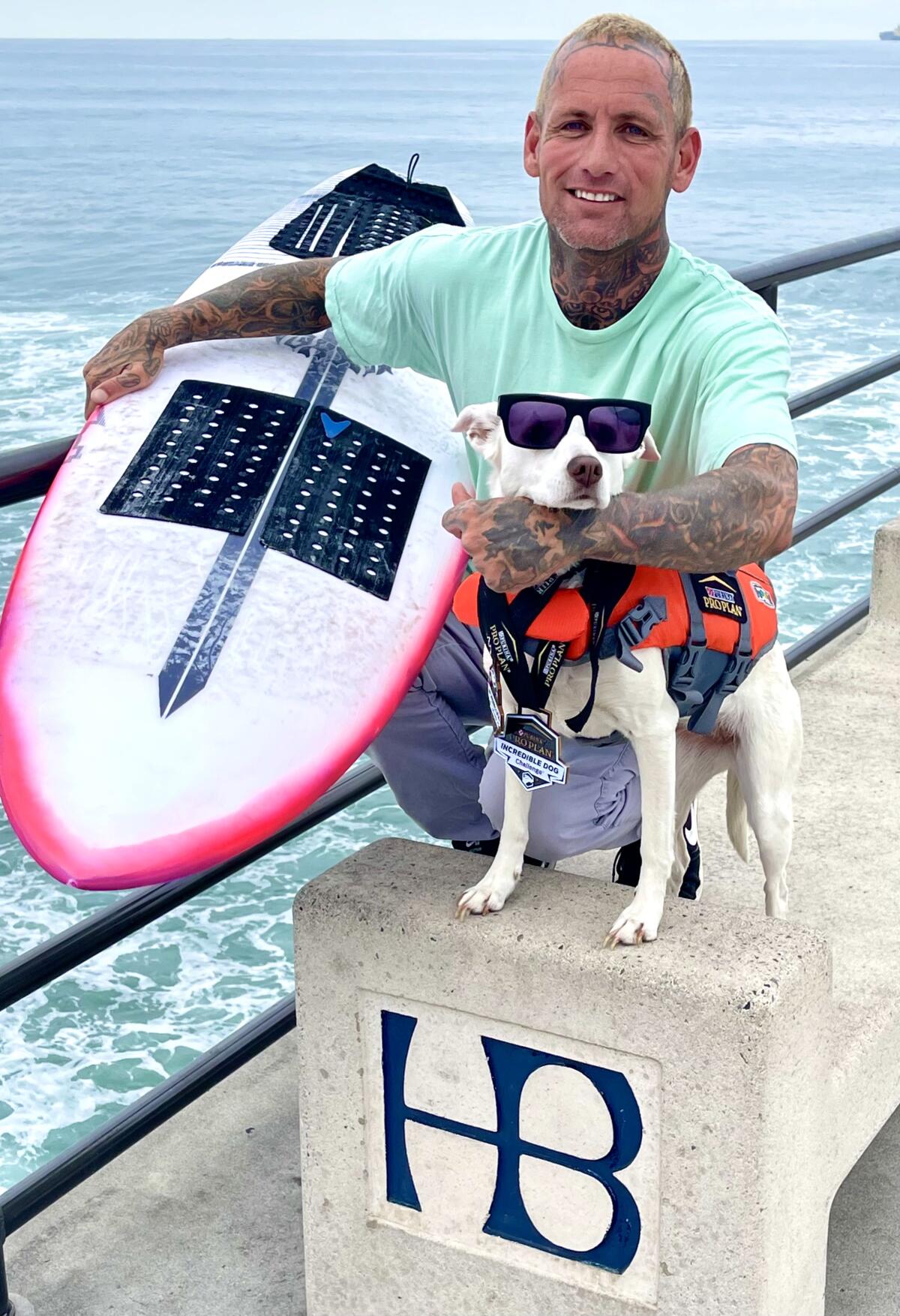 Trainer Ryan Rustan sits with Sugar the Surfing Dog on the Huntington Beach Pier on Friday.