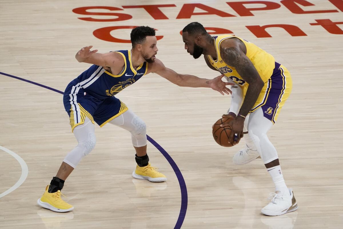 Lakers forward LeBron James looks to drive against Warriors guard Stephen Curry.