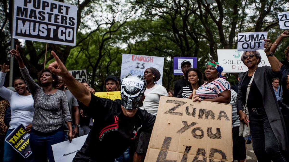 Demonstrators calling for South African President Jacob Zuma's resignation hold placards and shout slogans outside the Gupta family compound in Johannesburg on April 7.