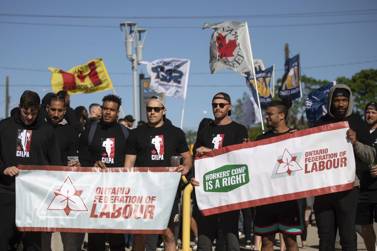 Members of the Canadian Football League Players Association (CFLPA), joined by local labor union representatives, demonstrate outside Tim Hortons Field in Hamilton, Ontario, on Tuesday, May 17, 2022. (Nick Iwanyshyn/The Canadian Press via AP)