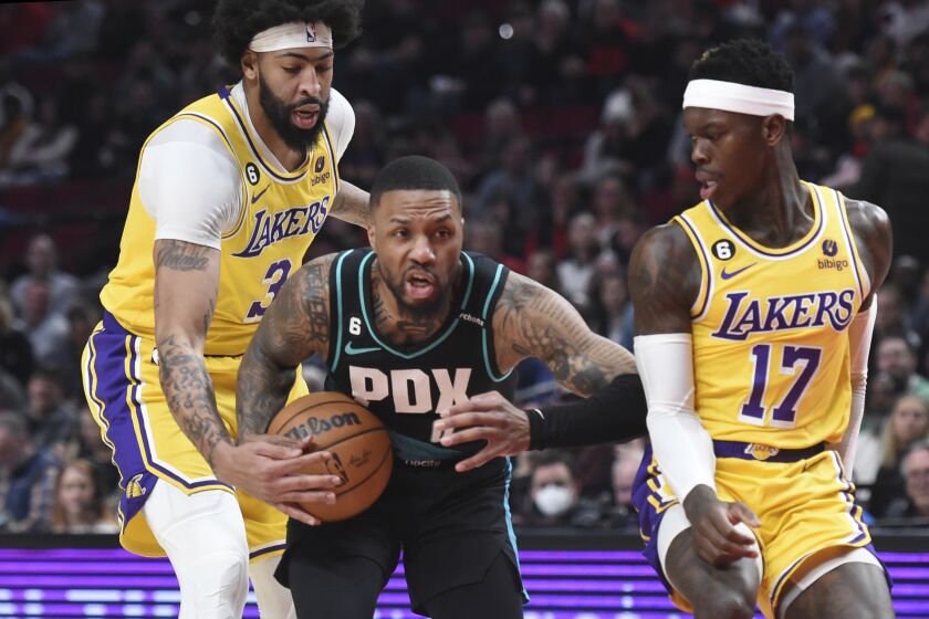 Portland Trail Blazers guard Damian Lillard, center, drives to the basket against Los Angeles Lakers forward Anthony Davis, left, and guard Dennis Schroder, right, during the first half of an NBA basketball game in Portland, Ore., Monday, Feb. 13, 2023. (AP Photo/Steve Dykes)