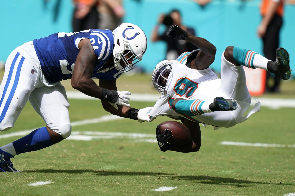 Indianapolis Colts defensive end Tyquan Lewis (94) brings down Miami Dolphins wide receiver Jakeem Grant (19), during the second half of an NFL football game, Sunday, Oct. 3, 2021, in Miami Gardens, Fla. (AP Photo/WIlfredo Lee)