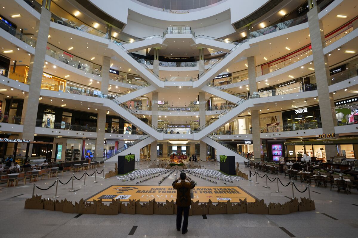 A shopper takes a picture at an empty shopping mall in Kuala Lumpur, Malaysia, Sunday, March 15, 2020. For most people, the new coronavirus causes only mild or moderate symptoms. For some it can cause more severe illness. (AP Photo/Vincent Thian)