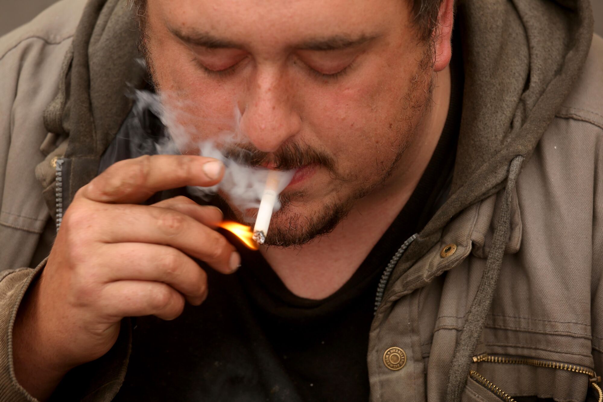 Andrew Truelove lights a cigarette shortly after waking up in a parking lot behind a strip mall in Torrance.