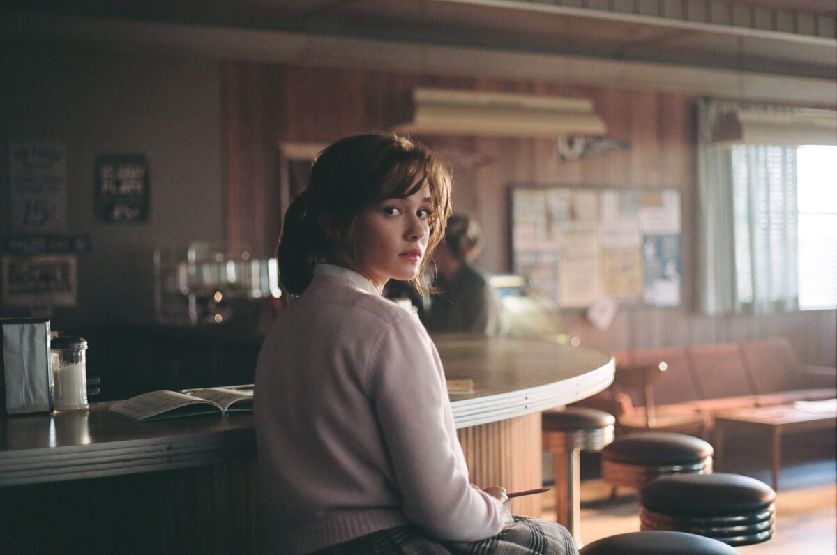 A woman sits in a diner.