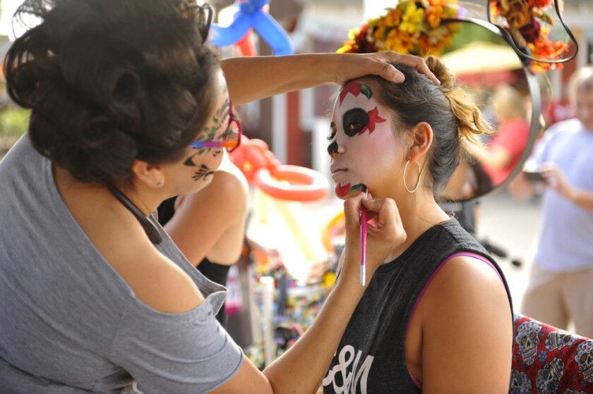A woman gets her face painted at Old Town's Dia de los Muertos celebration.