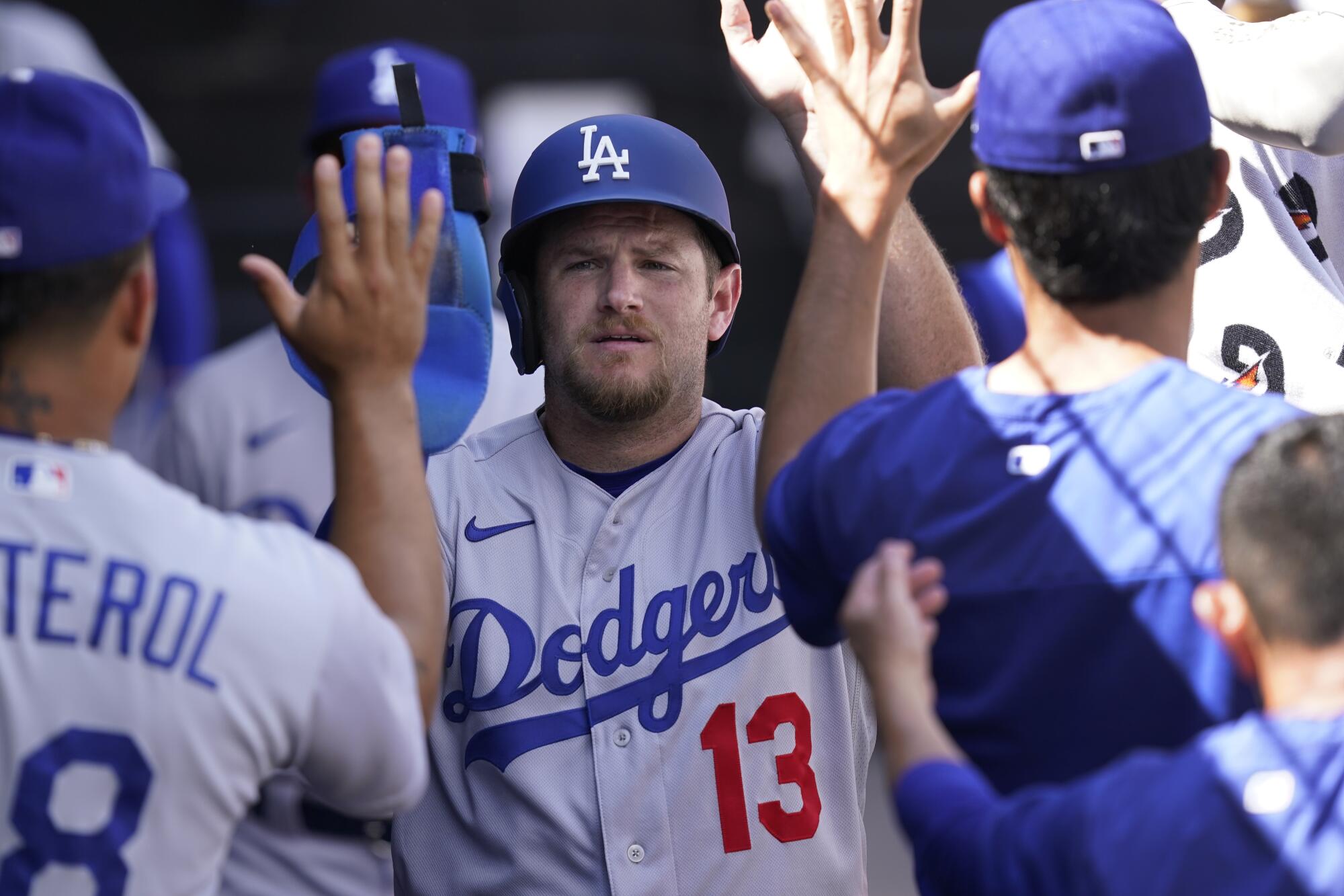 Max Muncy celebrates with teammates in the dugout after scoring on a wild pitch.
